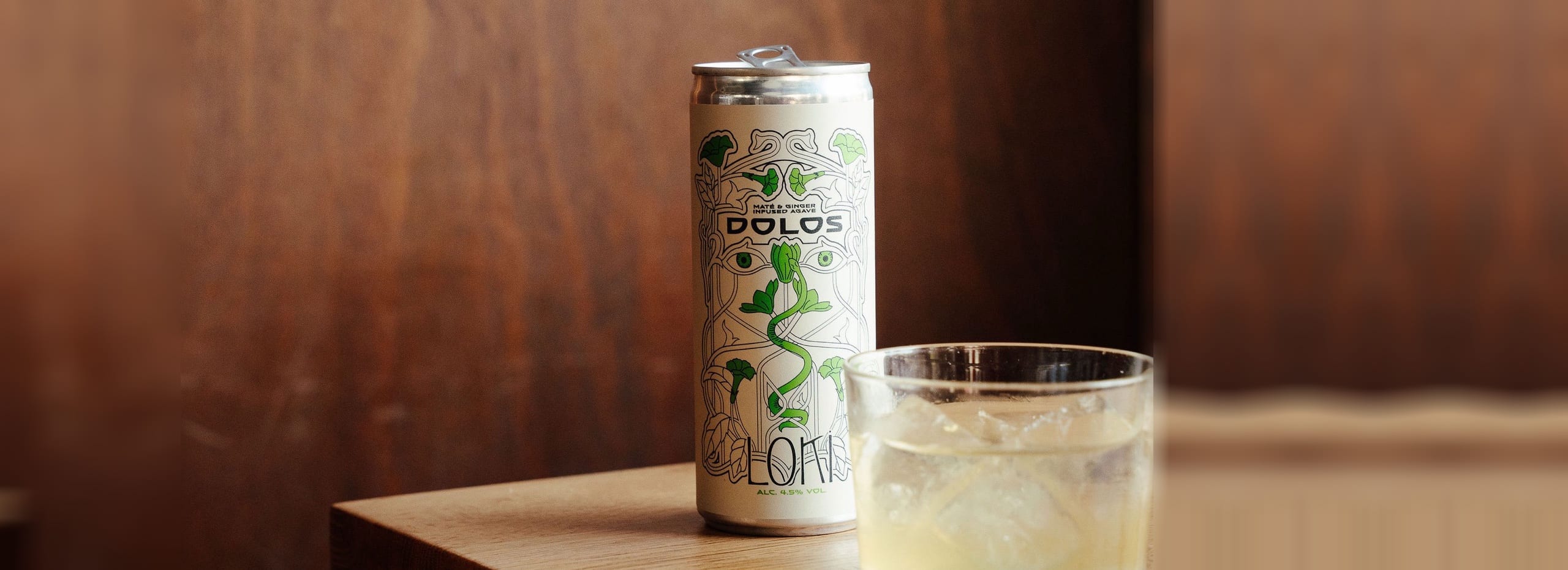 A can of Dolos Loki next to a glass with ice on a wooden table